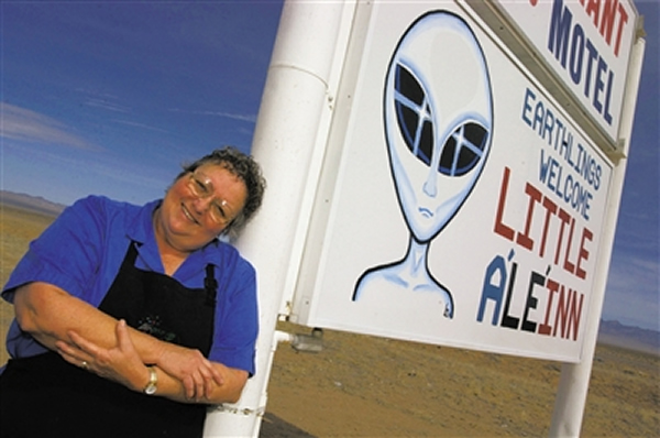 一名当地人在她的旅馆标志前,51区的传说刺激了当地旅游业。