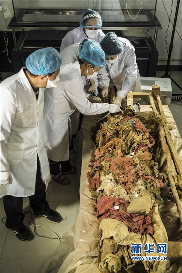 11月20日,来自中国丝绸博物馆、吐鲁番学研究院与吉林省博物院的多位考古专家小心翼翼地揭取古干尸身上的衣物。