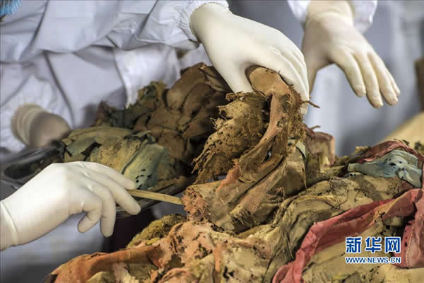11月20日,来自中国丝绸博物馆、吐鲁番学研究院与吉林省博物院的多位考古专家小心翼翼地揭取古干尸身上的衣物。