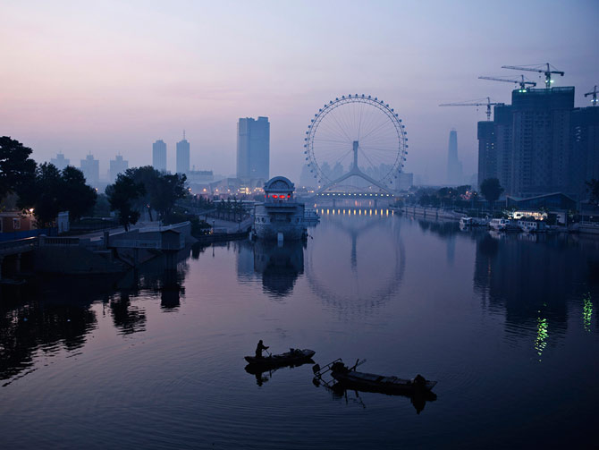 渔人在海河上捕鱼,一旁就是天津之眼摩天轮。为了吸引观光客,有一段运河被修复,并且引入了流经天津的海河之水。