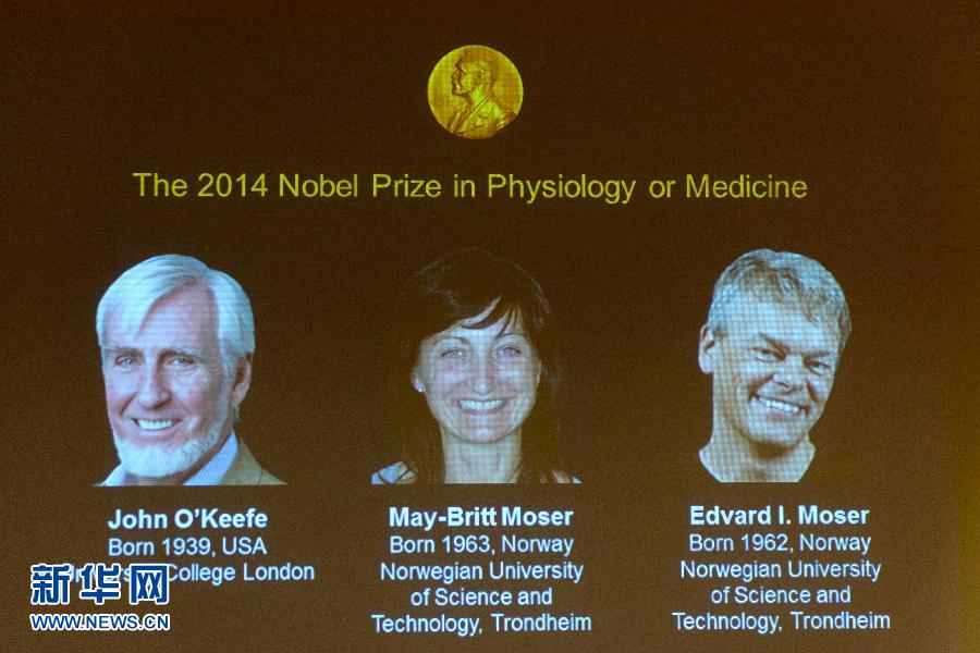 10月6日,在瑞典首都斯德哥尔摩,大屏幕上展示三位获奖者照片:约翰·奥基夫(左)、梅-布里特·莫泽(中)和爱德华·莫泽。