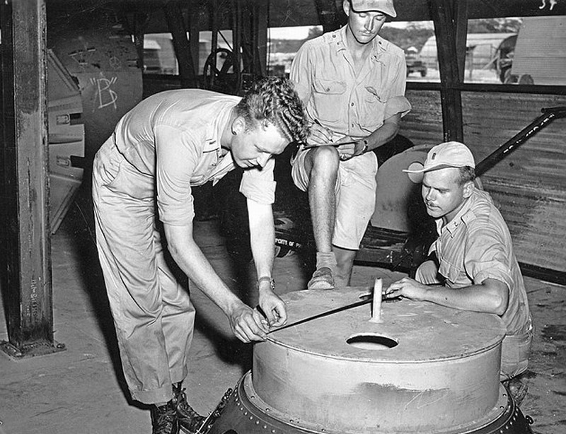 一群人正在日本南部马里亚纳群岛的提尼安岛上对原子弹外壳进行检查,美军从此地起飞袭击广岛和长崎