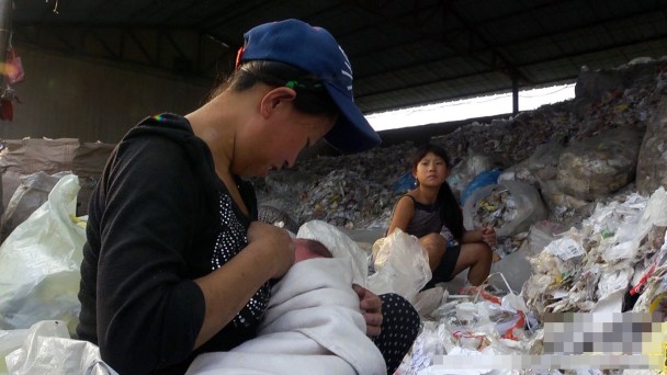 回收场内的工人在肮脏的工作地方喂哺孩子