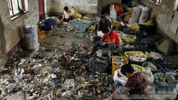 工人在环境恶劣的地方将塑胶分类