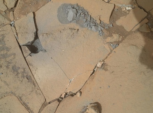 图为在“好奇”号钻孔过程中拍摄的照片,照片中可见钻孔后产生的浅灰碎石,以及岩石因钻孔震动所产生的裂缝。