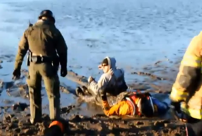狗主人(中)被拉回岸边脱险。