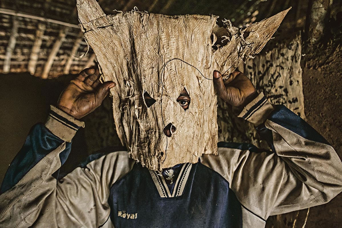 刚果民主共和国一座小村落的猎人调整他追踪猎物时所要戴的面具。食用受感染的野生动物是伊波拉病毒传给人类的途径之一。 Photograph by Pete Mull