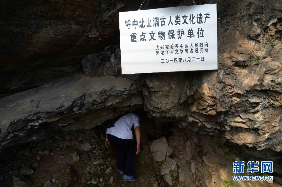 当地文物工作者弯腰进入北山洞洞口(7月23日摄)。