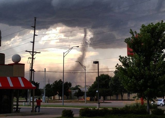 龙卷风吹近,卷起街上杂物,人们慌忙走避。