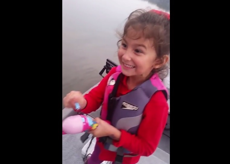 一脸紧张的艾华利,在父亲指导下绞动丝轮将鲈鱼拉近。