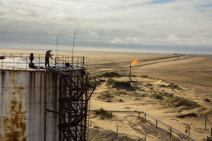 在俄罗斯的科古叶夫岛上,一名油田工人检查一座储油槽的液位;这座储油槽现在由乌拉尔能源公司所拥有。海滩后方就是巴伦支海。这座油田自1980年代中期便持续生产高品质