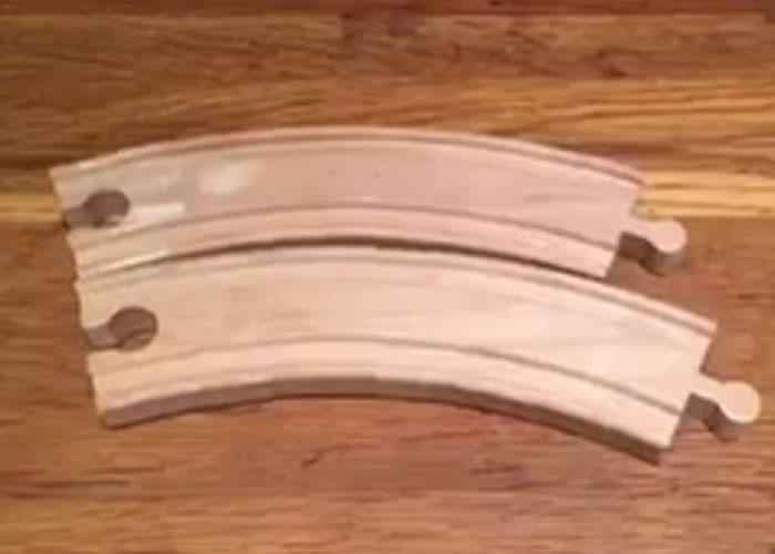 两块弧形玩具火车轨分置上下时,下方的一块看来明显长得多。