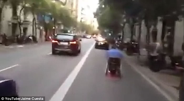 西班牙马路上演惊人一幕:坐轮椅男子在路上飞驰险象横生